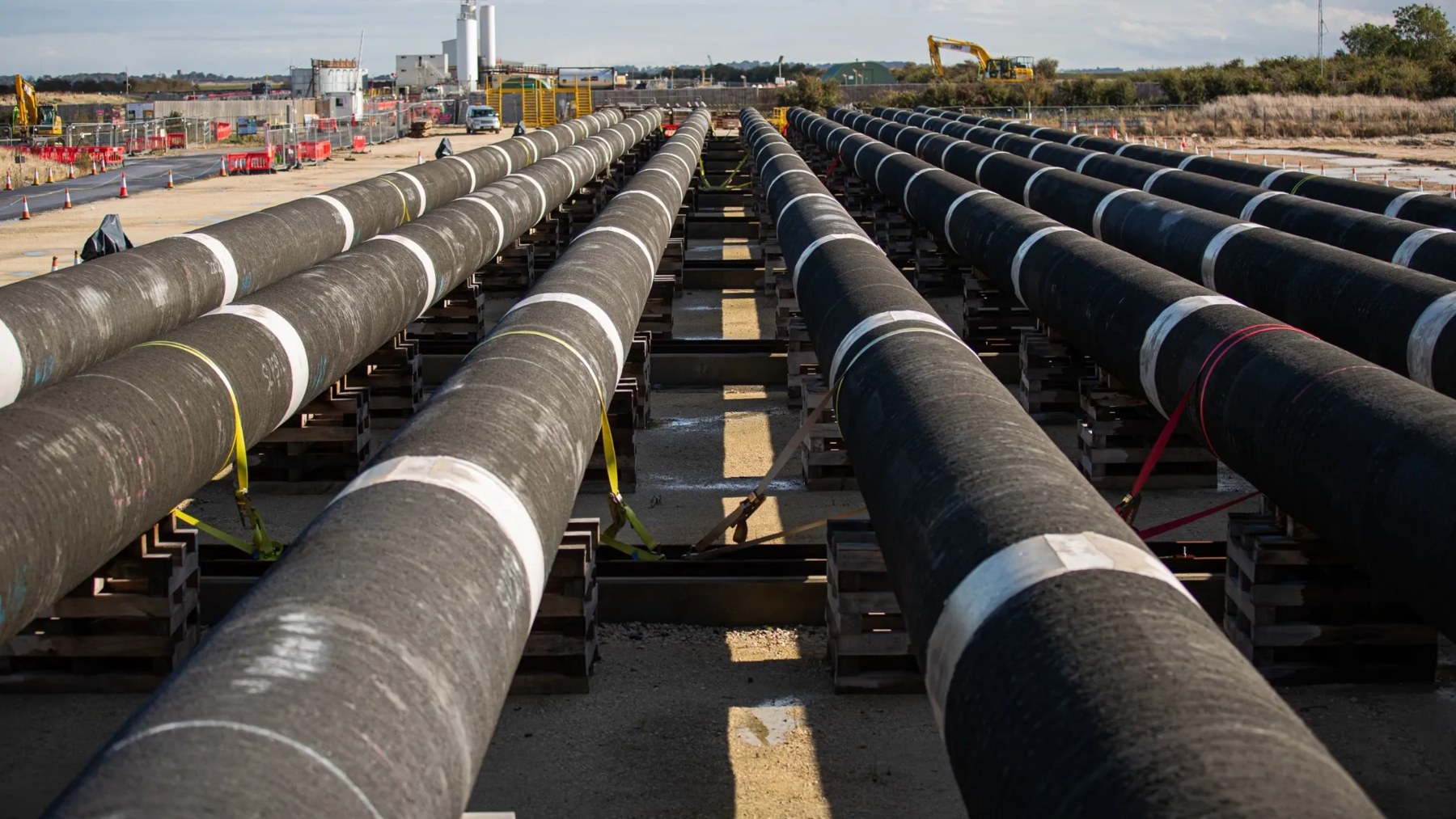 Long steel pipeline sections arranged on supports at a construction site